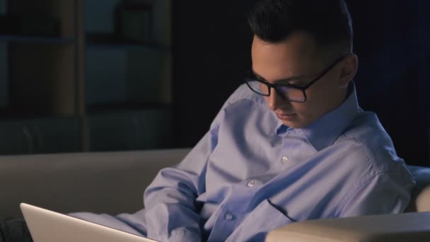 Egy férfi ül egy laptop, egy sötét irodában. Az ember dolgozik, késő estig - Felvétel, videó