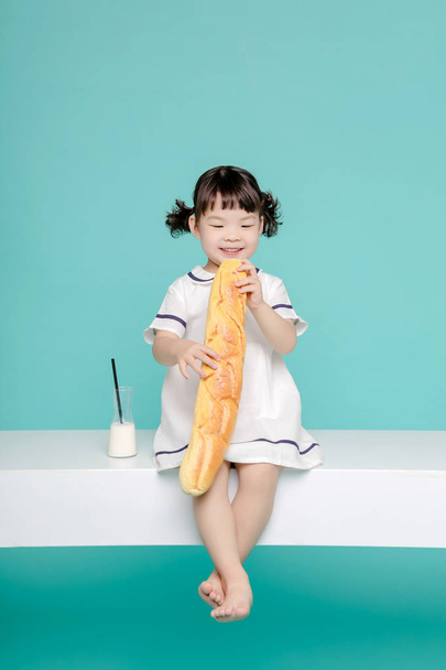Nevetve a portré, a tej és a kenyér, egészséges és boldog életmód szép ázsiai kislány. - Fotó, kép