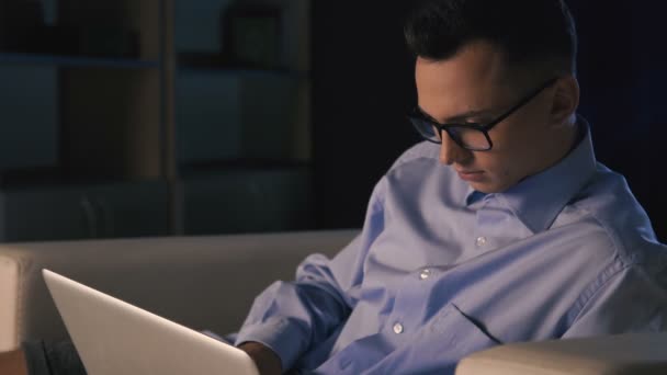 Um homem está sentado em um laptop em um escritório escuro. O homem trabalha até tarde.
 - Filmagem, Vídeo