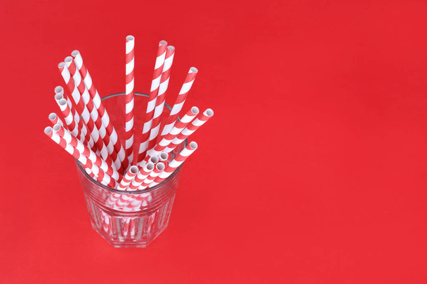 Red drinking straws in a glass with copy space. Celebration concept - Zdjęcie, obraz