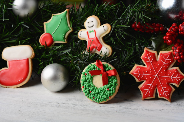 Close up view of Christmas cookies hanging under festive branches fir on wooden table.  xmas holiday concept. - Φωτογραφία, εικόνα