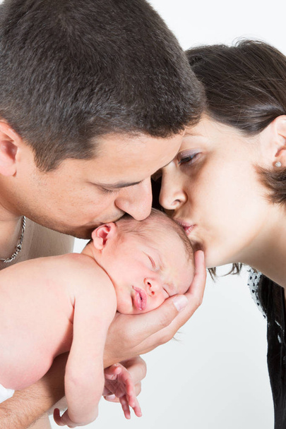 Young mother and father with newborn sleeping baby family kiss - Foto, Imagen