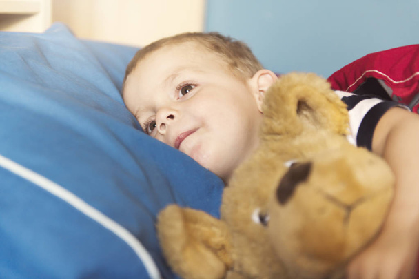 Child sleeping in his bed with teddy - 写真・画像