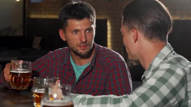 Dwóch mężczyzn przyjaciół ciesząc się picia piwa w lokalnym pubie - Materiał filmowy, wideo