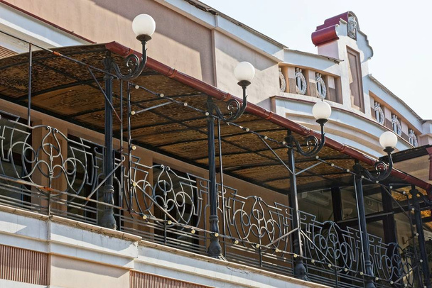 Große braune Balkon-Veranda mit schwarzem schmiedeeisernen Muster und Laternen - Foto, Bild