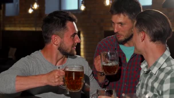 Grupa przyjaciół, uśmiechając się do kamery, trzyma się swojej szklanki piwa w barze - Materiał filmowy, wideo