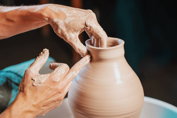 Unknown craftsman creates jug. Focus on hands only. Small business, talent, inspiration concept. Overhead view. Working process of mans work at potters wheel in art studio - Foto, Bild