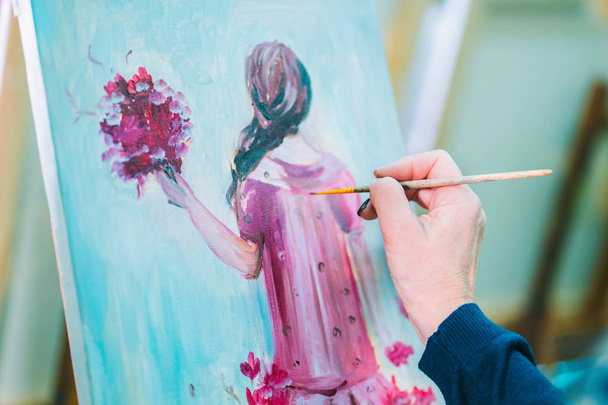 Woman paints a painting on canvas. Art academy or drawing school. Girl paints on the easel. Only hand of unknown artist, brush and canvas. - Фото, зображення