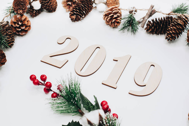 Christmas and New Year composition. 2019 simbols and fir branches with cones on white background. Flat lay, top view, copy space for text - Photo, image