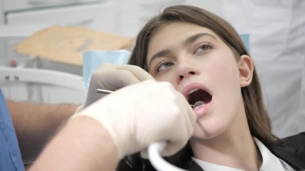 Portrait of a young beautiful girl in the dentist chair at dental clinic. Medicine, health, stomatology concept. dentist treating a patient. - Felvétel, videó