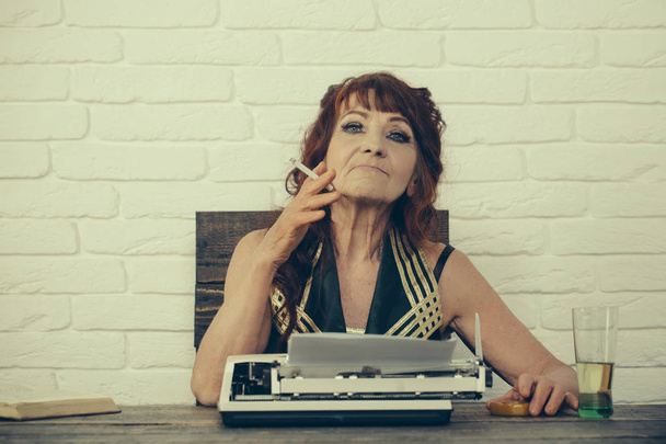 Article idea. Old woman work in writer office. Female reporter or journalist writing on typewriter. Senior woman type on retro typewriter. Journalist work in vintage office. Senior writer at desk - Photo, Image