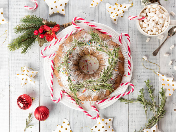 Traditional Christmas fruit cake on a white wooden table. Homemade pudding with festive decorations, candy canes - 写真・画像