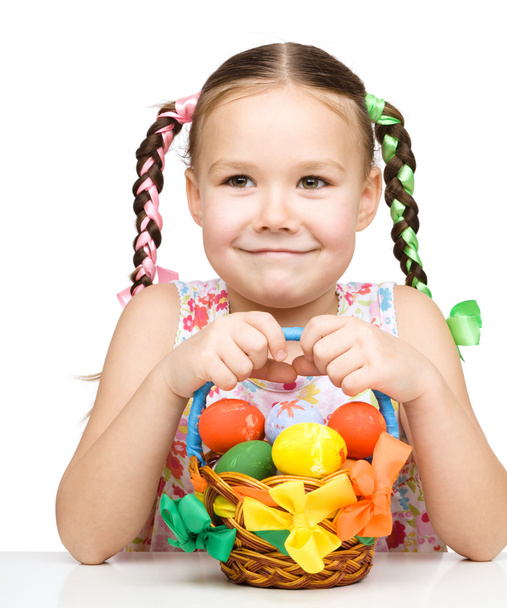 Little girl with basket full of colorful eggs - Foto, Imagen