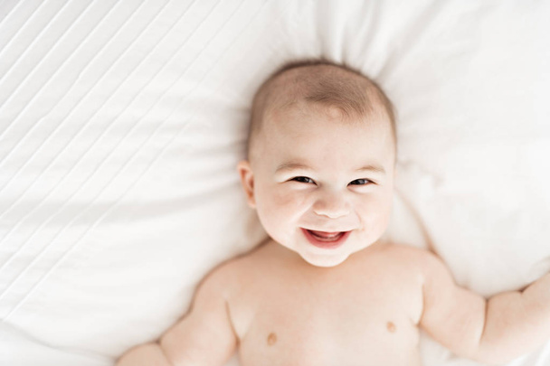 Portrait of a baby boy on the bed in bedroom - Photo, Image