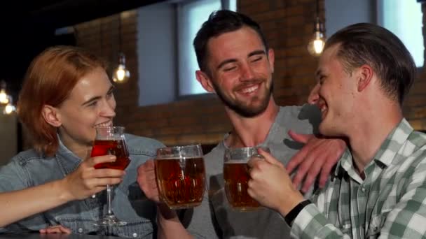 Szczęśliwych młodych ludzi brzęk ich piwa i uśmiecha się do kamery - Materiał filmowy, wideo