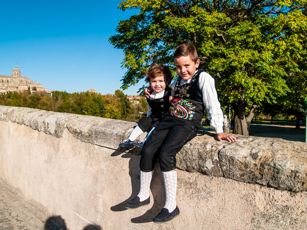 Dwoje dzieci bracia przyjęli na Roman bridge Salamanca, ubrani w tradycyjne stroje - Zdjęcie, obraz