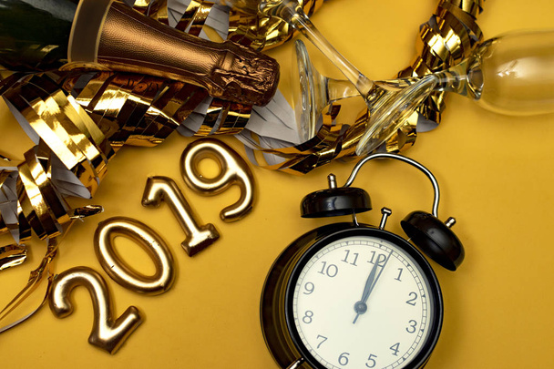 Neujahrskonzept. Nummer 2019 mit Uhr und goldenem Party-Accessoire auf gelbem Hintergrund. - Foto, Bild