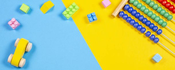 Детские игрушки рамка с плюшевым мишкой, деревянный игрушечный поезд, автомобиль, красочные кубики на синем и желтом фоне
. - Фото, изображение