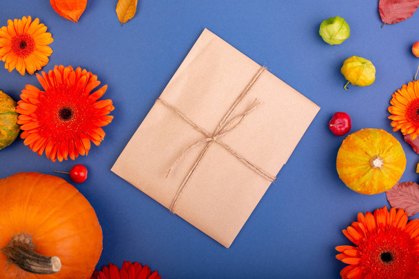 Ansicht der handgefertigten Geschenkbox mit gelben und orangefarbenen Blumen und Kürbissen auf blauem Hintergrund. leere Grußkarte für kreative Arbeitsgestaltung. flache Lage - Foto, Bild