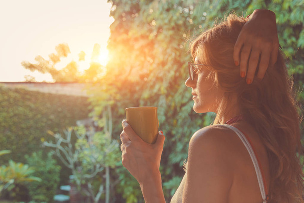 Roztomilá dívka se těší ranní kávu na verandě. - Fotografie, Obrázek