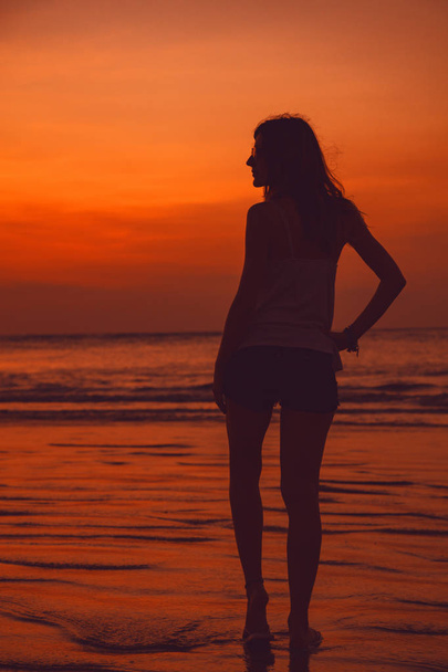 Silhouette of a girl in sunset / sunrise time over the ocean. - Foto, imagen