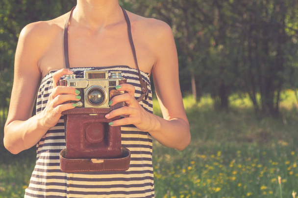 Girl holiding vintage / retro camera in nature. - Foto, afbeelding
