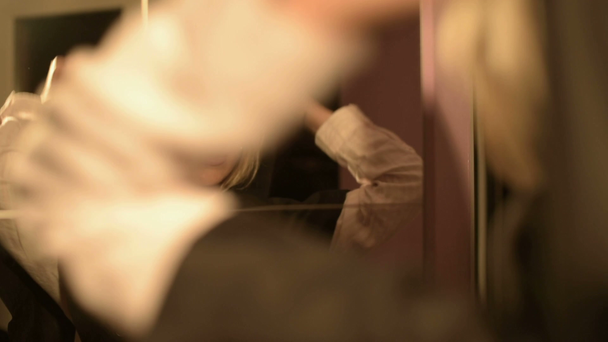 Közeli kép: egy lány bűvész a tükör előtt hozza a motorháztető, a ruhája időről időre. Élő kamera. Miszticizmus és a boszorkányság vagy a felkészülés - Felvétel, videó