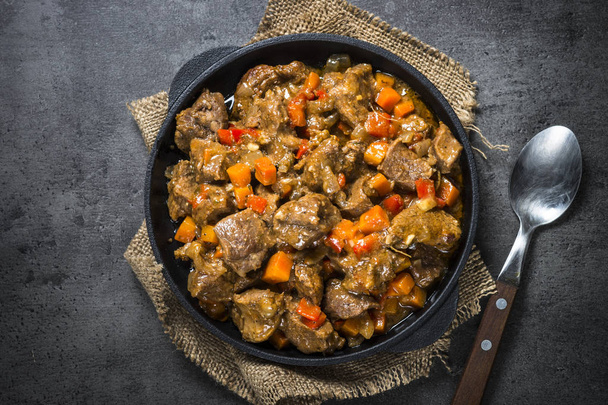 Beef stew with vegetables in iron pan on black. - Photo, Image