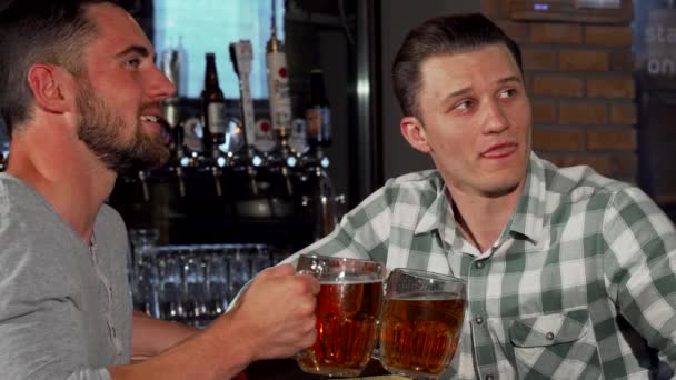 Vrolijke mannelijke vrienden kijken naar een spel aan de bar terwijl het hebben van bier - Video