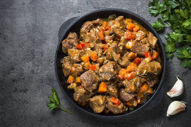 Beef stew with vegetables in iron pan on black. - Photo, Image