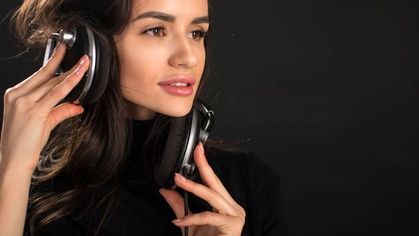 Fülhallgató hallgat disco DJ lány veri pózol stúdió sötét háttérhez képest. Fiatal vonzó kaukázusi nő modell területi védőnő - Fotó, kép