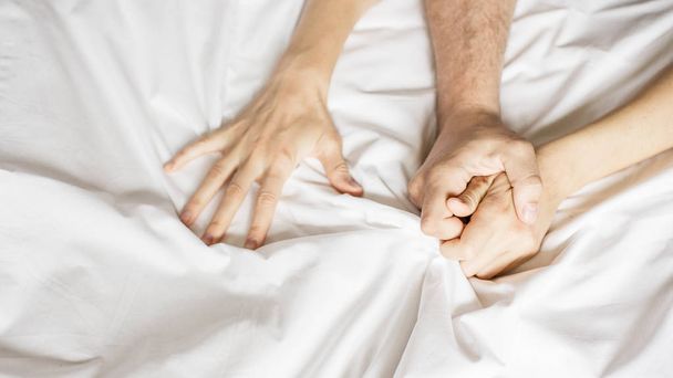 pary trzymać ręce razem w łóżku zbliżenie dotykając się wzajemnie na białe prześcieradła. Para seks - Zdjęcie, obraz