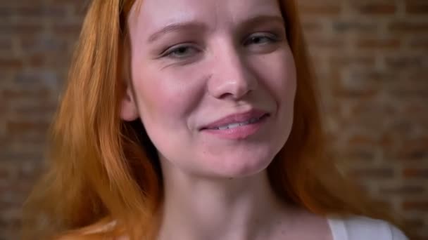 Pretty friendly smile of ginger caucasian woman, standing in light brown studio, casual wearing and artistic emotions indoor - Кадри, відео