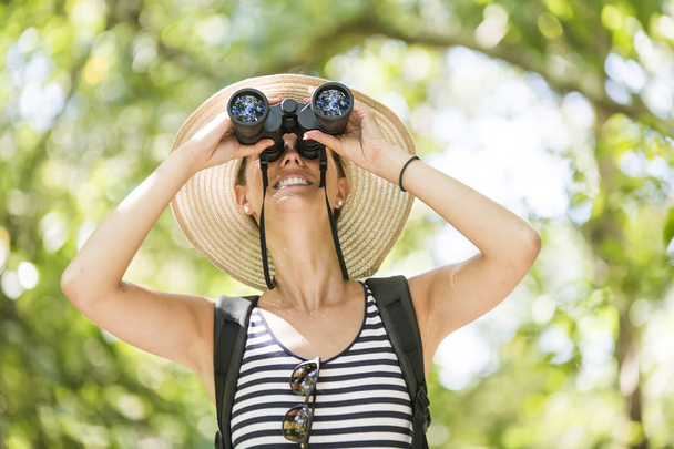 Tourists woman with Binoculars Looking for something along the forest - Fotografie, Obrázek