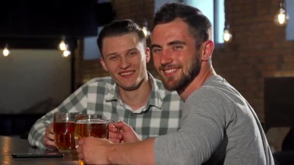Wesoły mężczyźni uśmiechając się do kamery, mając piwa w barze - Materiał filmowy, wideo