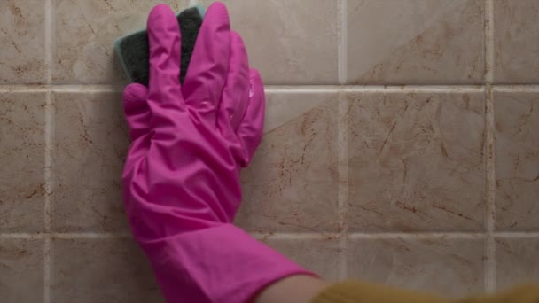Nahaufnahme der Reinigung der schmutzigen Fliesenwand mit der Hand im Gummihandschuh per Schwamm, Handel mit Haushaltschemikalien, Reinigung des Hauses, Schlamm und Fett - Filmmaterial, Video