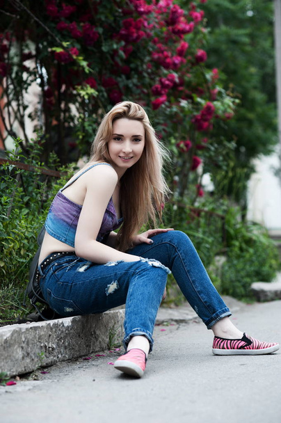 Beautiful sexy young blond woman in torn jeans posing on the streets of the old town - Фото, зображення