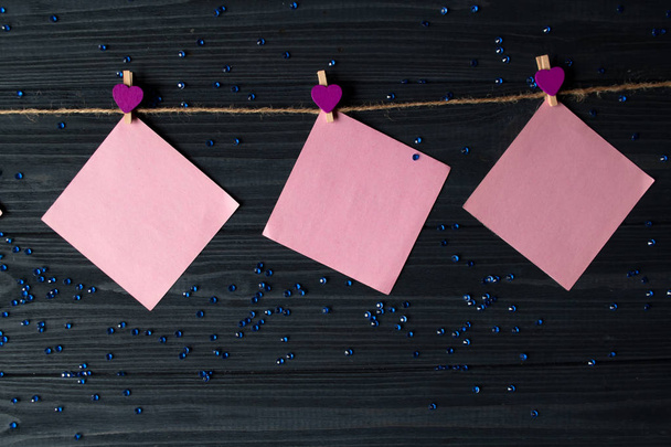 Rózsaszín memo-lapok összekapcsolni egy dekoratív pin egy sötét kék fa tábla. - Fotó, kép