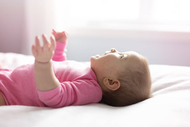 Baby girl lying on white sheet on the bedroom - Fotografie, Obrázek