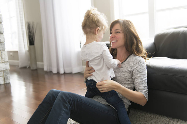 Happy mother with her baby daughter in the living room at home - Photo, Image