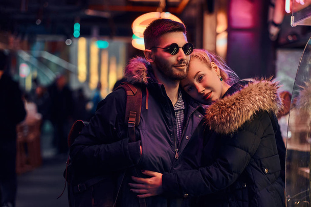 Привлекательная влюбленная пара. Красивая девушка обнимает своего парня стоя ночью на улице
. - Фото, изображение