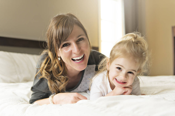 Mother and her daughter child girl taking good time on bed - Foto, immagini