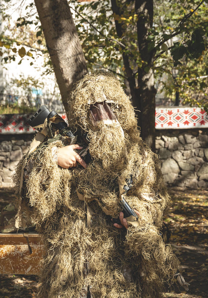 Un sniper camouflé garde son fusil. Soldat vêtu de ghillie camouflage sur la nature
. - Photo, image