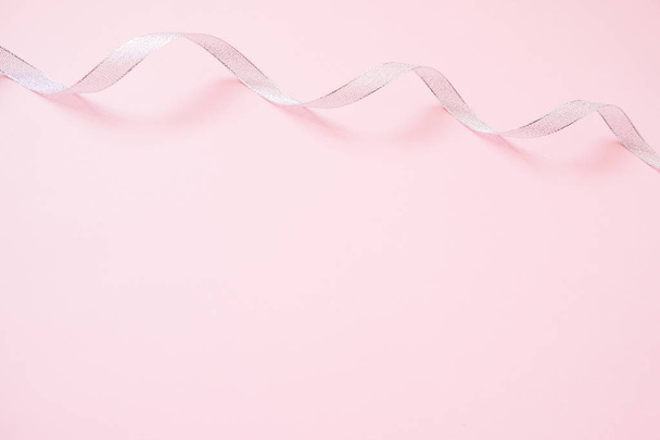 Silver streamers serpentine on pastel pink background. Christmas gift. Concept for celebration, carnival, party, festive sales. - Foto, afbeelding