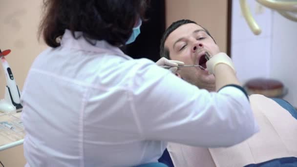 Крупним планом жіночий стоматолог робить процедури для пацієнта чоловічої статі в клініці
. - Кадри, відео