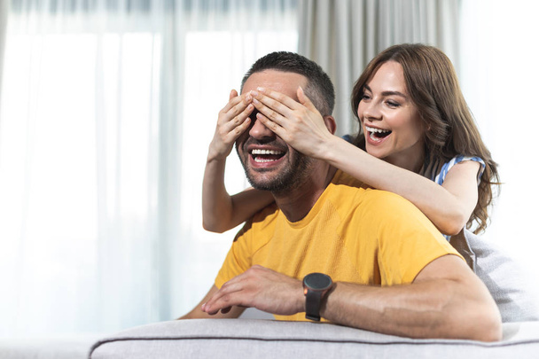 Riendo esposa está cerrando los ojos de su marido
 - Foto, imagen