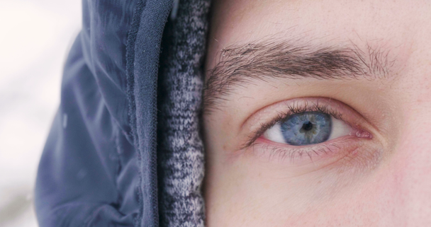 zbliżenie twarzy wideo strzał człowieka, częściowy widok twarzy z niebieskimi oczami, człowiek stojący na zewnątrz, w zimie  - Materiał filmowy, wideo