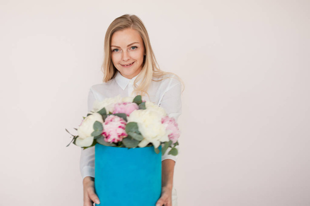 Woman with flowers in a hat box. Bouquet of peonies. Girl in business style, receives flowers or gives, Blue box. - Fotografie, Obrázek