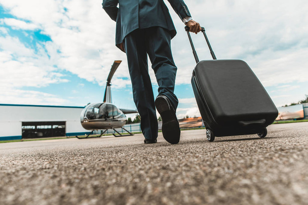 Close up of elegant man carrying his luggage on the helicopter platform - Foto, afbeelding