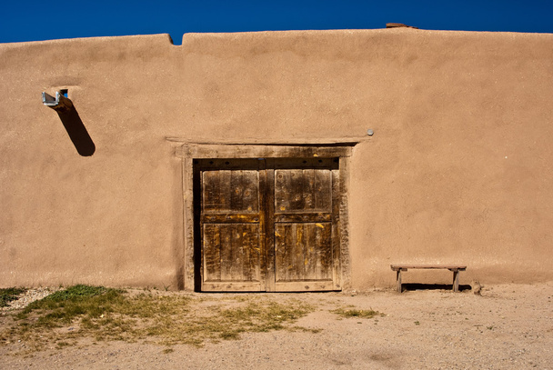 Adobe gebouw met oude deur en Bank - Foto, afbeelding